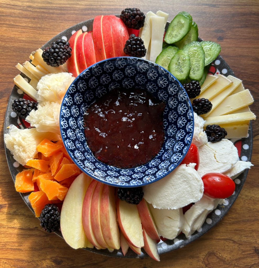 a cheese plate with a bowl of jam in the center