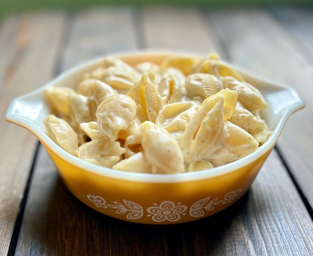 an orange bowl filled with shells in cheese