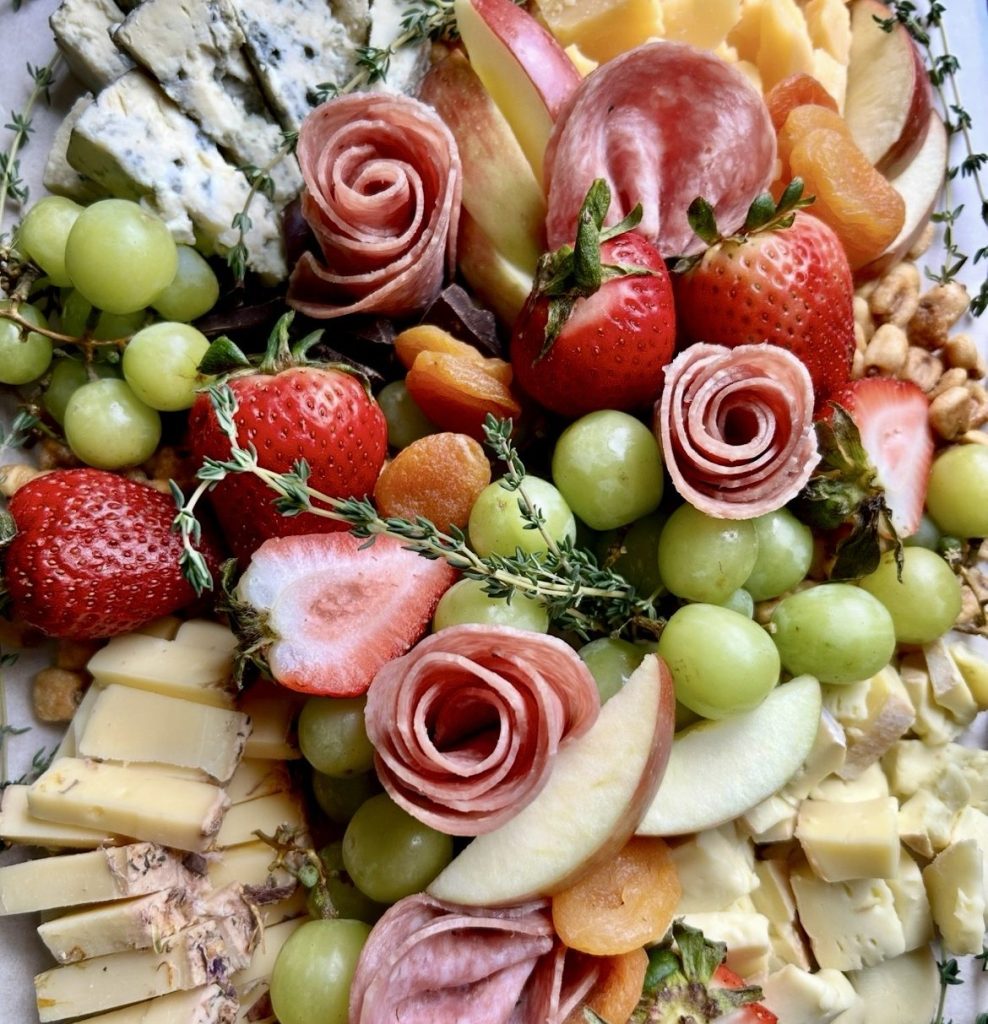 a charcuterie plate of various cheeses, meats, and fruits