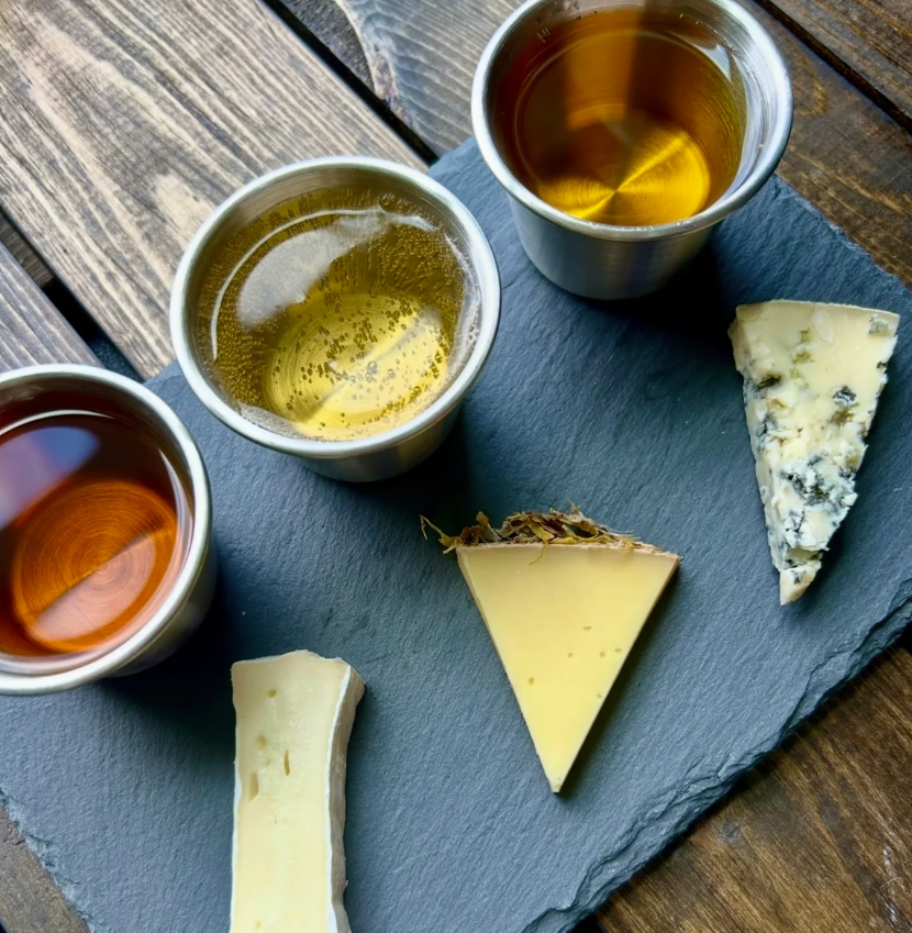 three cheeses paired with three meads on a black slate 